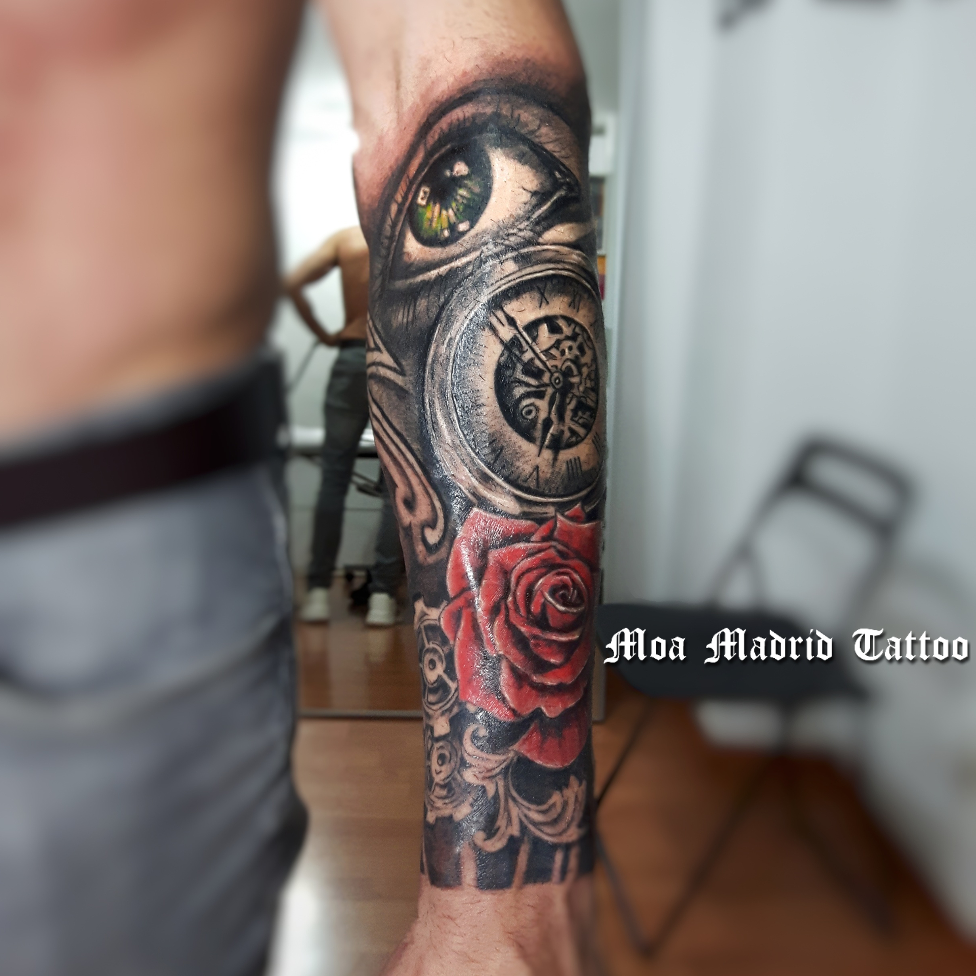 Tatuaje con ojo, reloj y rosa rosa en el antebrazo